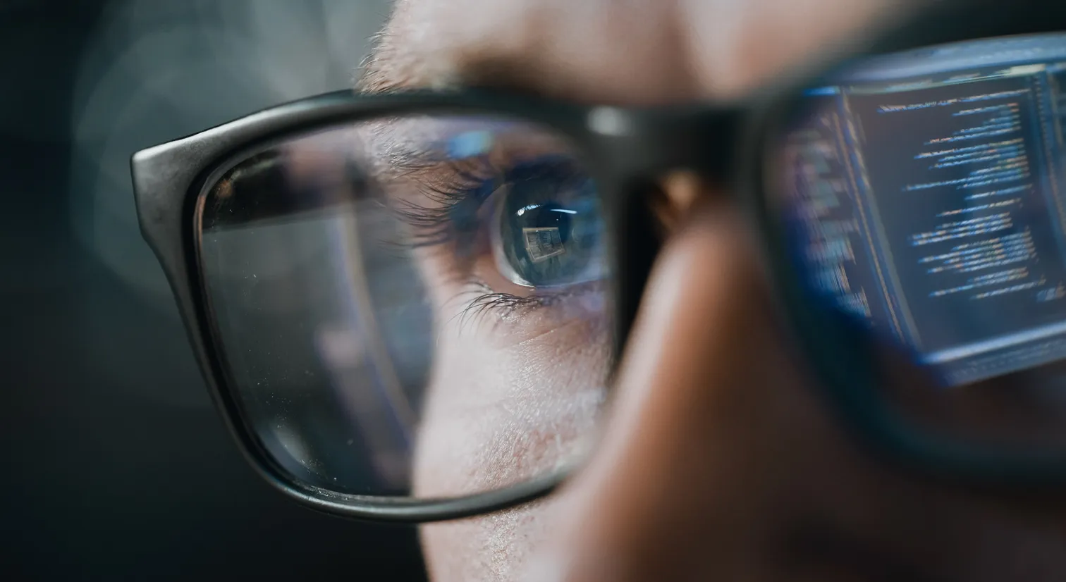 Man wearing glasses with one lens reflecting source code